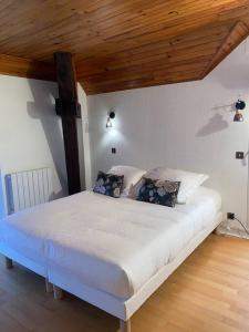 Cama blanca en habitación con techo de madera en Villa sans soucis, en Gérardmer