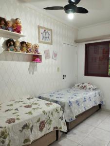 a bedroom with two beds and dolls on a shelf at Apartamento na Frente da Praia in Itanhaém