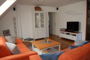 a living room with an orange couch and a table at Ferienwohnung Oberdeck in Fehmarn