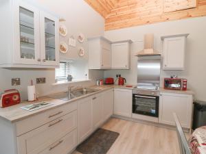 a kitchen with white cabinets and a wooden ceiling at Oak Tree Cottage in Enniscorthy