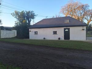 a white house with a black door on a yard at Oak Tree Cottage in Enniscorthy