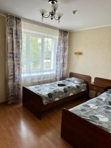 1 dormitorio con 2 camas y ventana en Duets en Daugavpils