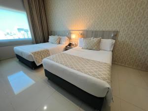 a hotel room with two beds and a window at Hotel Dorado Plaza Alto Prado in Barranquilla