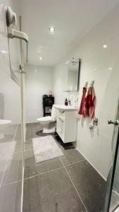 Baño blanco con lavabo y aseo en Newly built amazing apartment, en Järfälla
