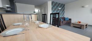 une table en bois avec des assiettes et des verres à vin dessus dans l'établissement T3 “Belle-île“- 50 m de la plage de Fort Bloqué/Ploemeur, à Ploemeur