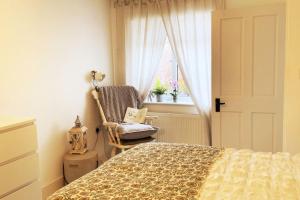 a bedroom with a bed and a chair and a window at Beautiful 1 bed annex, near beach and shops in Iford