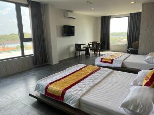 a hotel room with two beds and a table and chairs at Hotel Stylish Tân Khai in Hớn Quản