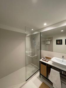 uma casa de banho com uma cabina de duche em vidro e um lavatório. em Magnólia 75 em Leça da Palmeira