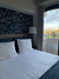 a bedroom with a white bed and a window at Magnólia 75 in Leça da Palmeira