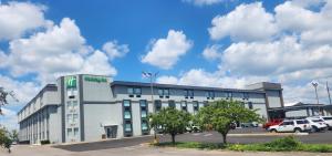 a large white building with cars parked in a parking lot at Holiday Inn St Louis SW - Route 66, an IHG Hotel in Saint Louis