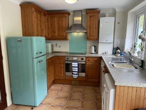 a kitchen with a blue refrigerator and a sink at Driftwood in Porthtowan