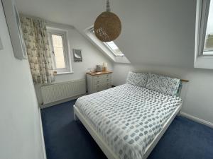a small bedroom with a bed and two windows at Driftwood in Porthtowan