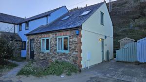 a small brick and stone house with blue windows at Driftwood in Porthtowan