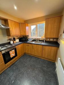 een keuken met houten kasten en een fornuis met oven bij Beautiful two bed home in Marsh in Lindley