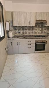 Una cocina con gabinetes blancos y piso de baldosas. en Rooms in shared apartment close to CMN-Airport, en Dah Hammou Ben Cheïkh
