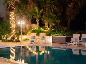 a pool at night with chairs and lights at Villa Alexandra - Sunset Sea Views, Heated Jacuzzi, Sauna and Gym in Mellieħa