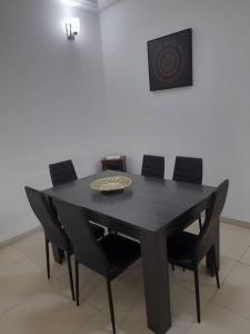 a black dining room table with black chairs at Cosy F3 au point E in Dakar