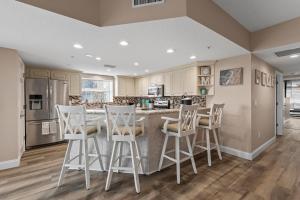 a kitchen with white bar stools and a counter at Oceanwalk 1-401 in New Smyrna Beach