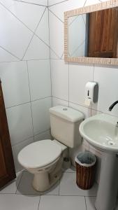 a white bathroom with a toilet and a sink at Pousada Sobre as Ondas - ILHA DO MEL - PR in Ilha do Mel