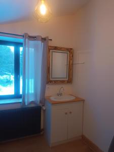 ein Bad mit einem Waschbecken, einem Spiegel und einem Fenster in der Unterkunft Les étoiles de Bevy Gîtes in Lajoux