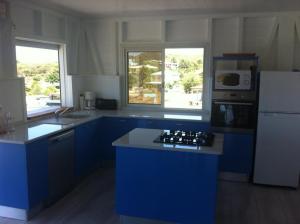 a kitchen with blue cabinets and a white refrigerator at Villa QUIETUDE in Sainte-Anne