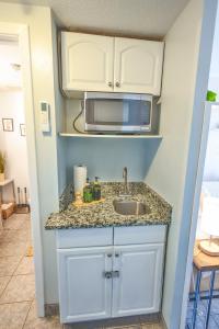 a kitchen with a sink and a microwave at stylish luxe condo! in Fort Walton Beach