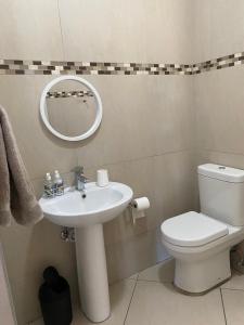 uma casa de banho com um lavatório, um WC e um espelho. em Makyle's Selfcatering Apartment em Windhoek