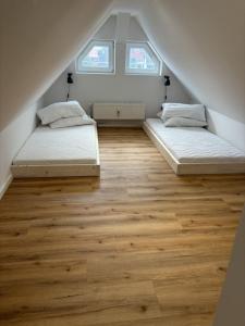 2 łóżka w pokoju na poddaszu z drewnianą podłogą w obiekcie Wurmbergblick Ferienwohnung w mieście Braunlage