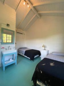 a bedroom with two beds and a sink and a mirror at Hidden Island Hostel in Tigre