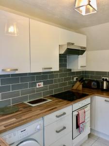 a kitchen with white cabinets and blue tiles at Cosy 3 bed detached house Birmingham in Birmingham