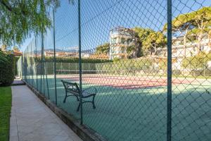 a bench on a tennis court behind a fence at H11 [Verde Giada] Piscina - Tennis - Parcheggio in Sanremo