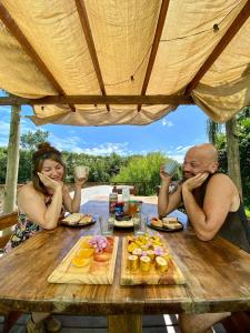 a man and a woman sitting at a table with food at Hidden Island Hostel in Tigre
