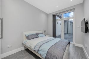 a white bedroom with a bed and a window at Your Cosy Stay Modern 3 Double Bedroom Apartment - Fully Furnished - 5 Mins walk to Stn in London