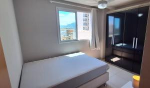 a bedroom with a white bed and a window at LINDO APT 3q FRENTE A PRAIA in Guarapari