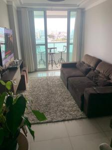 a living room with a brown couch and a television at LINDO APT 3q FRENTE A PRAIA in Guarapari