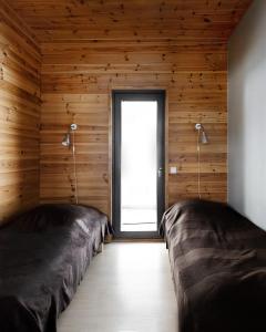 2 camas en una habitación con paredes de madera y ventana en Ameno 2, Himos by DG Lomailu, en Jämsä