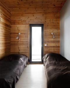 two beds in a room with wooden walls and a window at Ameno 2, Himos by DG Lomailu in Jämsä