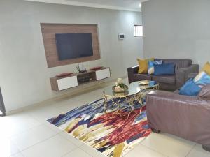 sala de estar con 2 sofás y TV de pantalla plana en The Packwood Cottage, en Johannesburgo