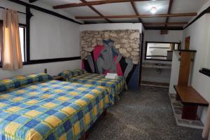 1 dormitorio con 2 camas y pared de piedra en Hotel Cabañas Safari, en Palenque