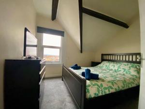 a bedroom with a bed with a dresser and a window at Aisha’s Attic in Rhyl