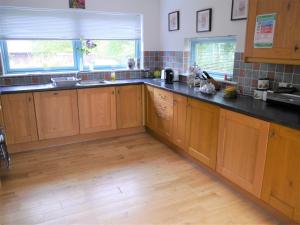 a kitchen with wooden cabinets and black counter tops at Ptarmigan Cottage in Aviemore