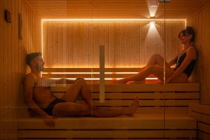 a man and woman sitting in a sauna at Hotel Al Madarig in Castellammare del Golfo