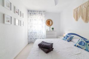 ein weißes Schlafzimmer mit einem großen weißen Bett mit blauen Kissen in der Unterkunft Apartº Roquetas de Mar 1º linea playa in Roquetas de Mar