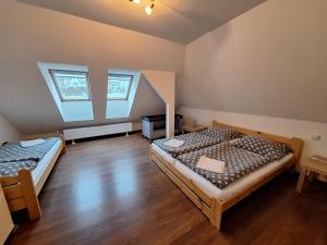 two beds in a room with wooden floors and two windows at Apartmány Paseky - Jablonec nad Nisou in Jablonec nad Nisou