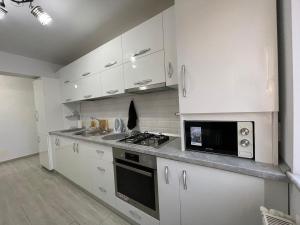 a kitchen with white cabinets and a sink and a microwave at Traveler’s Luxury Home in Suceava +7 photos