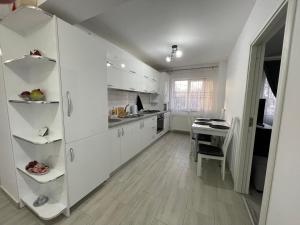 una cucina con mobili bianchi e tavolo di Traveler’s Luxury Home a Suceava