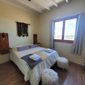 a bedroom with a large bed with two white ottomans at Casona Islas Blancas in Camarones