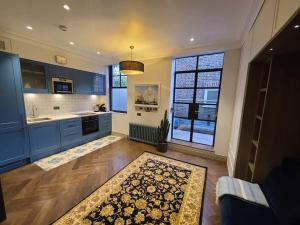 a kitchen with blue cabinets and a rug on the floor at New Boutique Ground Floor Apartment in London