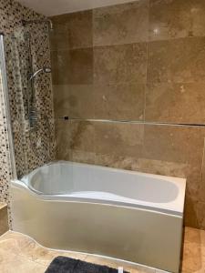 a white bath tub in a bathroom with a shower at Gracehill Suite in London