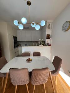 a white dining room table with chairs and a clock at Downtown Apartment in Strumica